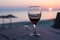 Glass with red wine and Sunset on beach at the background. summertime vacation concept