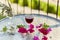 Glass of red wine on terrace. Decorative pink flowers and a branch of an olive tree in a glass. Romantic concept. Top