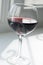 A glass of red wine on a white background with a play of shadows