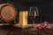 A glass of red wine with a wooden wine barrel, a large piece of Swiss cheese