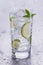 Glass of refreshing cold mineral water with pieces of lime