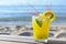 Glass of refreshing drink with kiwi and mint on wooden bench near sea. Space for text