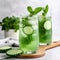 Glass of refreshing green drink with cucumbers and mint leaves on a table
