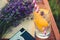 A glass of refreshing lemonade, vintage cameta, a book and freshly cutted lavender flowers over a wooden chair.