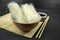 Glass rice noodle in a bowl, asian kitchen background with bamboo mat, chopsticks, soy sauce on black background