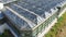 Glass roof of a greenhouse. Aerial drop down with tilting camera. Botanical garden in summer