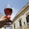 Glass of rose wine in man`s hand against a blue sky background. Close-up. Relaxed mood concept in the historical italian city