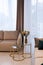 Glass round bedside table with gold with a vase of flowers in a modern beige interior. Interior Design. Soft selective focus,