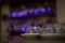 Glass round utensils candlesticks on white saucers, made. Against the background of the purple lights of the bar