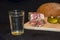 Glass of russian vodka and snack lard bream pickled cucumbers onion garlic bread on a wooden board on a black background