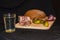 Glass of russian vodka and snack lard bream pickled cucumbers onion garlic bread on a wooden board on a black background