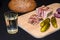 Glass of russian vodka and snack lard bream pickled cucumbers onion garlic bread on a wooden board on a black background