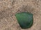 Glass on the sand. On the sand of the shells lies a fragment of a green bottle. A sea-worn piece of glass. Natural texture