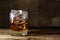 Glass of scotch whiskey with ice cubes on a rustic wooden table