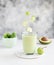 Glass of smoothie with avocado cucumber and flying apple slices on a light background