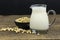 A glass of soymilk with soybeans on wooden table background