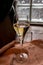 Glass of sparkling white wine champagne or cava with bubbles and classic wooden champagne pupitre rack with empty bottles on