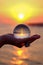 Glass sphere in the palm with an inverted reflection of the sunset on the sea in Turkey in Kizilagac