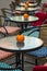 Glass tables of an outdoor cafe with pumpkins and colored cushions of chairs