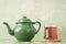 A glass of tea and green enamel teapot
