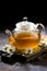 glass teapot of fragrant chamomile tea and dark background