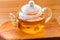 Glass teapot with herbal chamomile tea close-up on wooden board background
