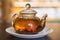 Glass teapot of invigorating fresh fragrant tea on a brown wooden table