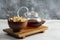 A glass teapot of tea with wooden bowl full of crackers