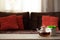 Glass teapot on wooden table against defocused sofa with pillows. Front view. Mock-up