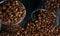 Glass transparent cup full of brown coffee beans, many coffee beans on a black background. Close-up. View from above