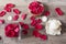 Glass vase and wood bow filled with red rose petals, white aromatic vanilla candle. Wooden background. Aromatherapy concept.