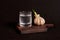 A glass of vodka and a sprouted head of garlic on a wooden stand