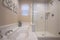 Glass walled shower stall and shiny bathtub inside the bathroom of a home