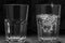 Glass with and without water on a black background. The concept of optimism and pessimism