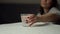 Glass of water with a dissolving tablet. Close-up. In the background, a pain-ridden woman rubs her temples.