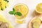 Glass of water, infused with lemon and ginger on light wooden table.