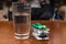 Glass of Water on Table Beside Stack of Pills