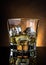 Glass of whiskey on black table with reflection, warm atmosphere dark light