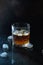 Glass of whiskey or bourbon with ice on black stone table. Glass of whiskey with ice and a square decanter. Glass of scotch