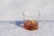 Glass of whiskey with ice on a bed of snow and white background, close up