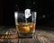 Glass of whiskey with ice cubes on a wooden table. An old tabletop with light and a glass of strong drink.