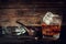 Glass of whiskey with ice and pipe on a wooden background.