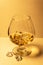 A glass of whiskey with ice on a white table. Strong alcohol with ice. Vintage close-up of golden cognac. Cognac, whiskey, wine, b