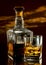 Glass of whiskey and stylish bottle on dark glassy table