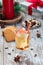 Glass of white glogg or mulled wine with apple slices and cinnamon stick, gingerbread cookies and gift box on background, vertical
