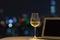 A glass with white wine puts on sofa with laptop computer with colorful bokeh light from city