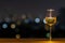 A glass of white wine on wooden table of rooftop bar with colorful bokeh of city light and space for text