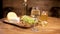 A glass of white wine on a wooden table served with cheese and grapes