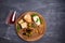 Glass of wine with cheese, olives, bread, nuts and basil on dark background.