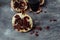 A glass of wine on a gray background among pomegranates. Close pomegranate and red pomegranate seeds